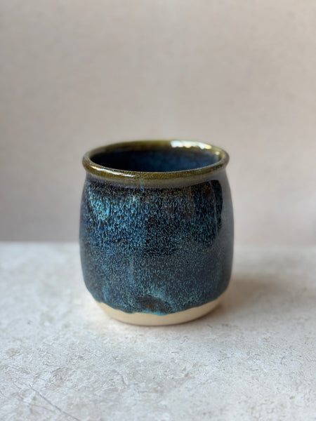 Blue ceramic cup on a light gray surface with a neutral background