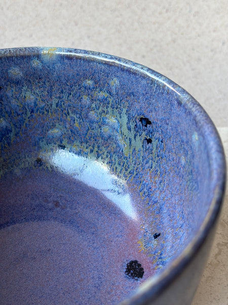 Close-up of a blue ceramic bowl with speckled pattern on a light gray background